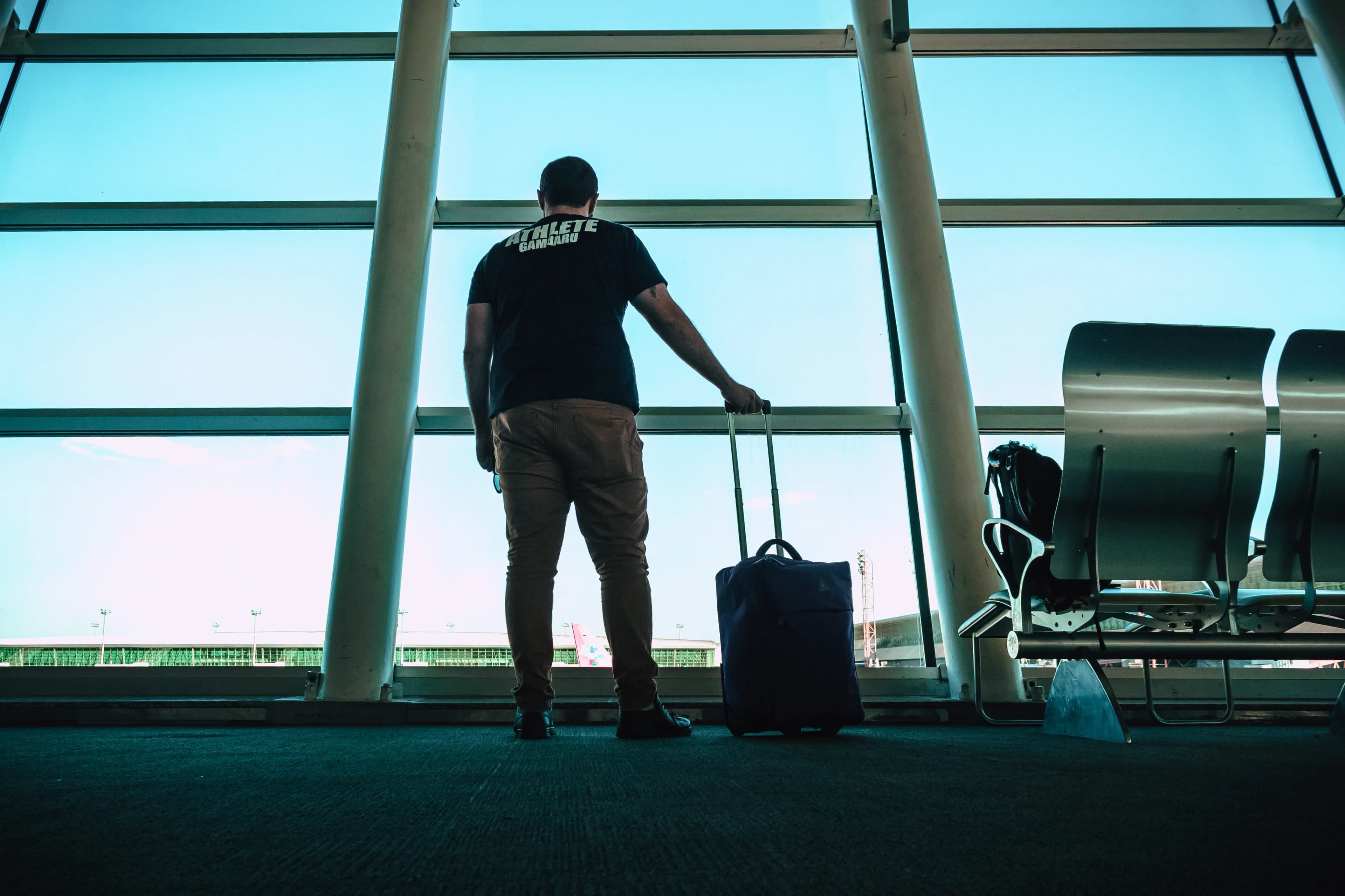 Viajera con mochila esperando su vuelo frente al ventanal de un aeropuerto