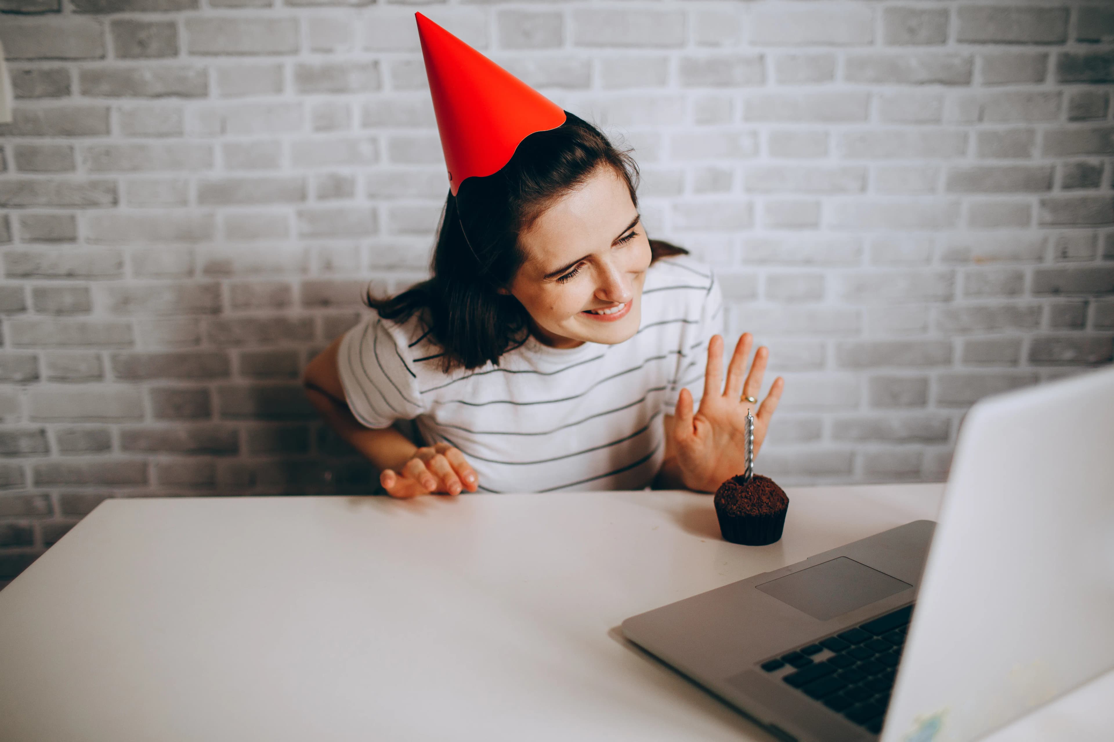 Mujer joven trabajando en una laptop sobre una mesa mientras organiza los detalles de una fiesta en casa
