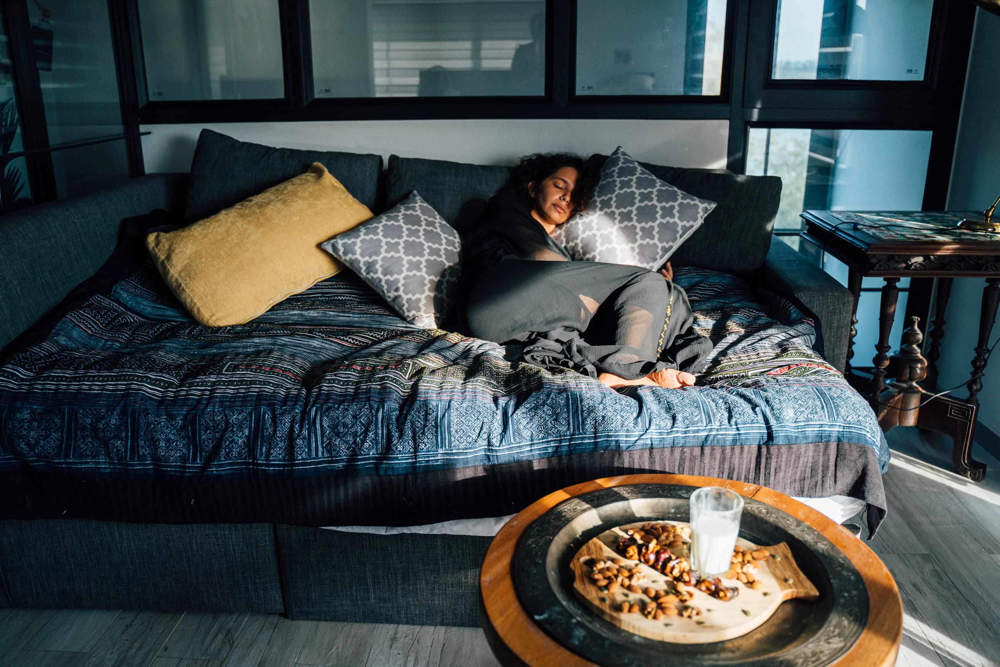 Mujer joven durmiendo una siesta corta recostada en el sofá de la sala con luz de día