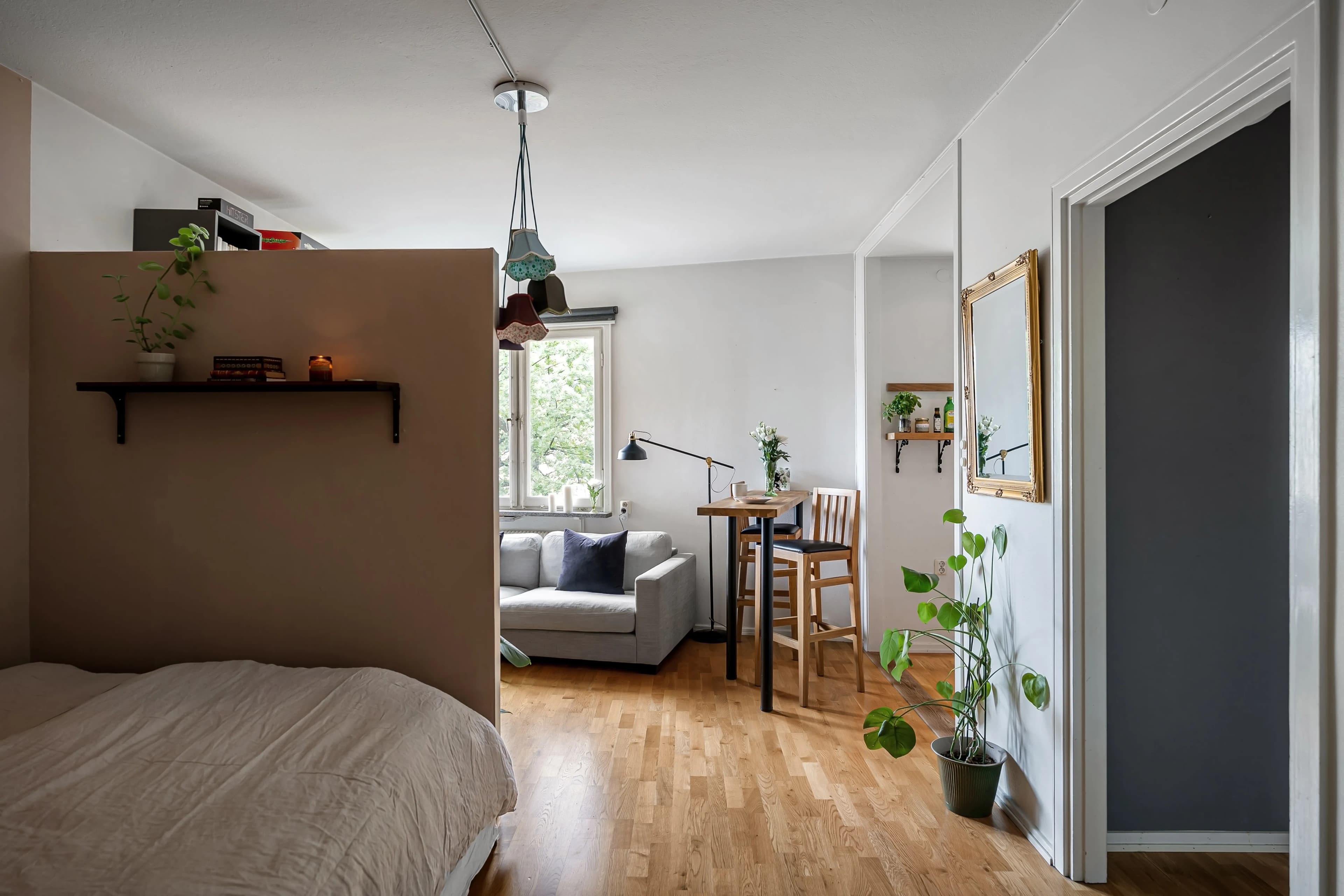 Sala pequeña de un departamento con sofá compacto, tapete y luz natural de una ventana alta
