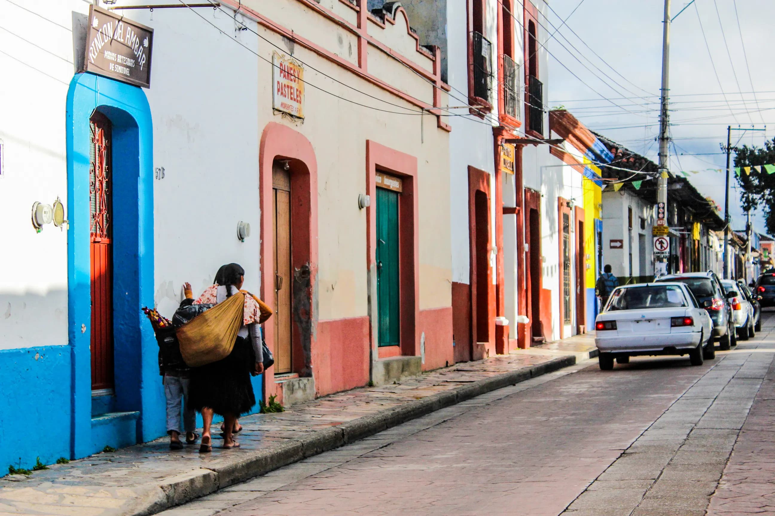 Viajera con mochila caminando por una calle empedrada de un centro histórico mexicano